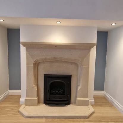 Stone fireplace alcove lit with recessed spotlights