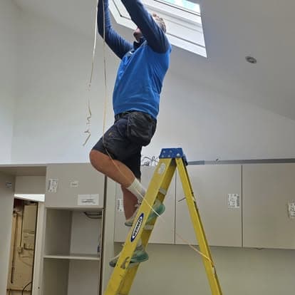 John fitting ceiling lighting from a stepladder